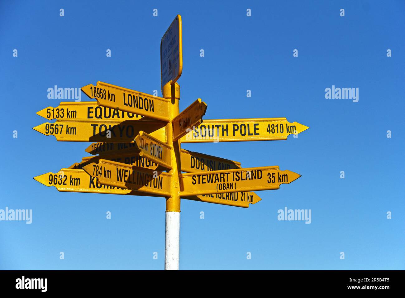 Un posto con i cartelli stradali gialli che mostrano le varie direzioni. Bluff, Nuova Zelanda. Foto Stock