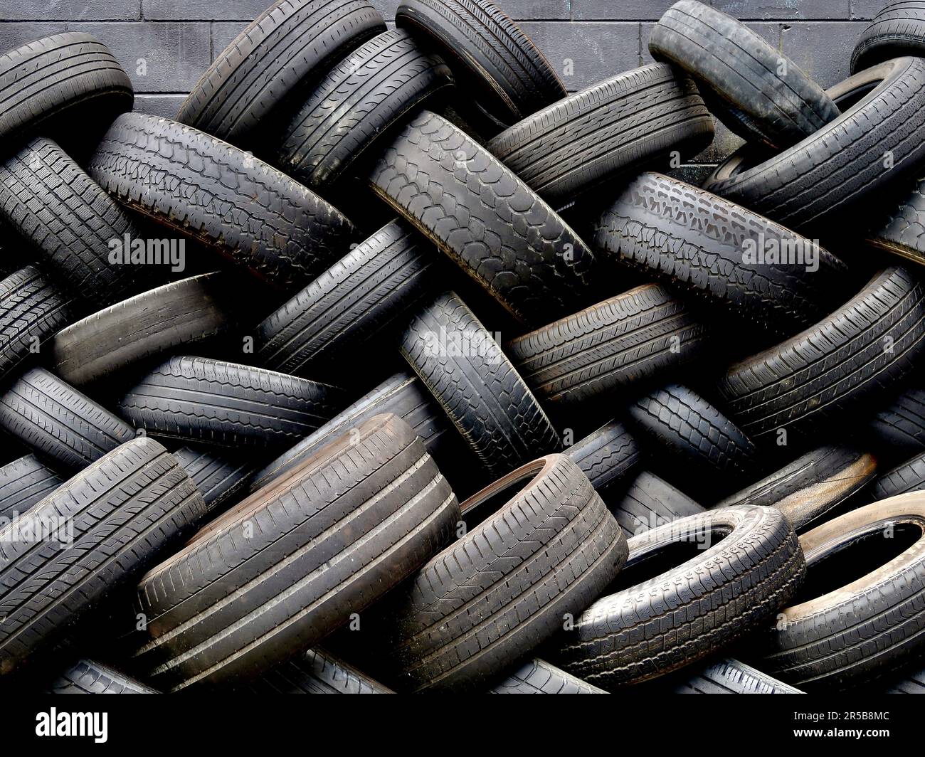 Un grande mucchio di pneumatici di automobile scartati disposti in una pila ordinata contro uno sfondo bianco Foto Stock