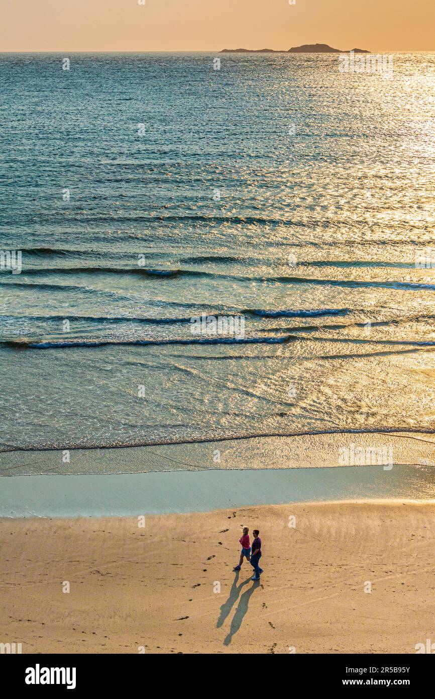 Una giovane coppia a piedi al tramonto sulla spiaggia di Whitesands Bay, una spiaggia Bandiera Blu sulla penisola di St David nel Pembrokeshire Coast National Par Foto Stock