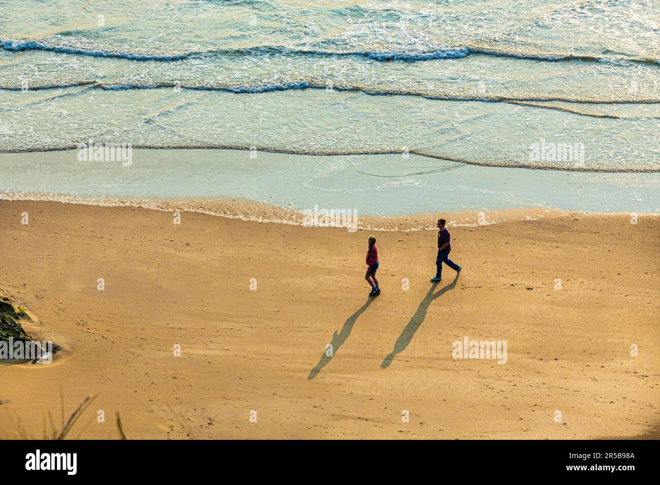 Giovani coppie che camminano al tramonto sulla spiaggia di Whitesands Bay, una spiaggia con bandiera Blu, la penisola di St David, il Pembrokeshire Coast National Park, West Wales Foto Stock