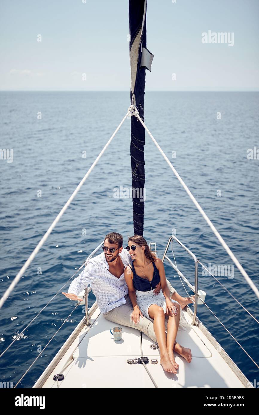 Una giovane coppia innamorata seduta sulla prua dello yacht e godendo di una splendida vista mentre si viaggia in una bella giornata di sole sul mare. Estate, mare, vacanza Foto Stock
