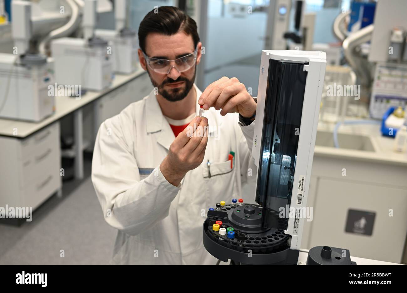 PRODUZIONE - 23 maggio 2023, Hesse, Darmstadt: Tecnico di laboratorio chimico Florian Große lavora su un gascromatografo per la determinazione della purezza dei solventi in un laboratorio del gruppo farmaceutico e tecnologico Merck KGaA, con sede a Darmstadt. Il laboratorio di controllo qualità per solventi ad alta purezza nel settore Life Science di Merck verifica la qualità dei solventi da utilizzare nei laboratori di ricerca o nell'industria farmaceutica. Foto: Arne Dedert/dpa Foto Stock