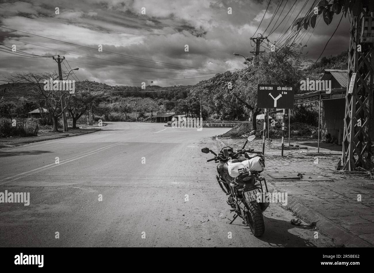 Una grande motocicletta parcheggiata vicino a un cartello stradale blu sulla strada QL40 che punta ai confini della Cambogia e del Laos in Bo Y comune, Ngoc Hoi distretto, nel cent Foto Stock