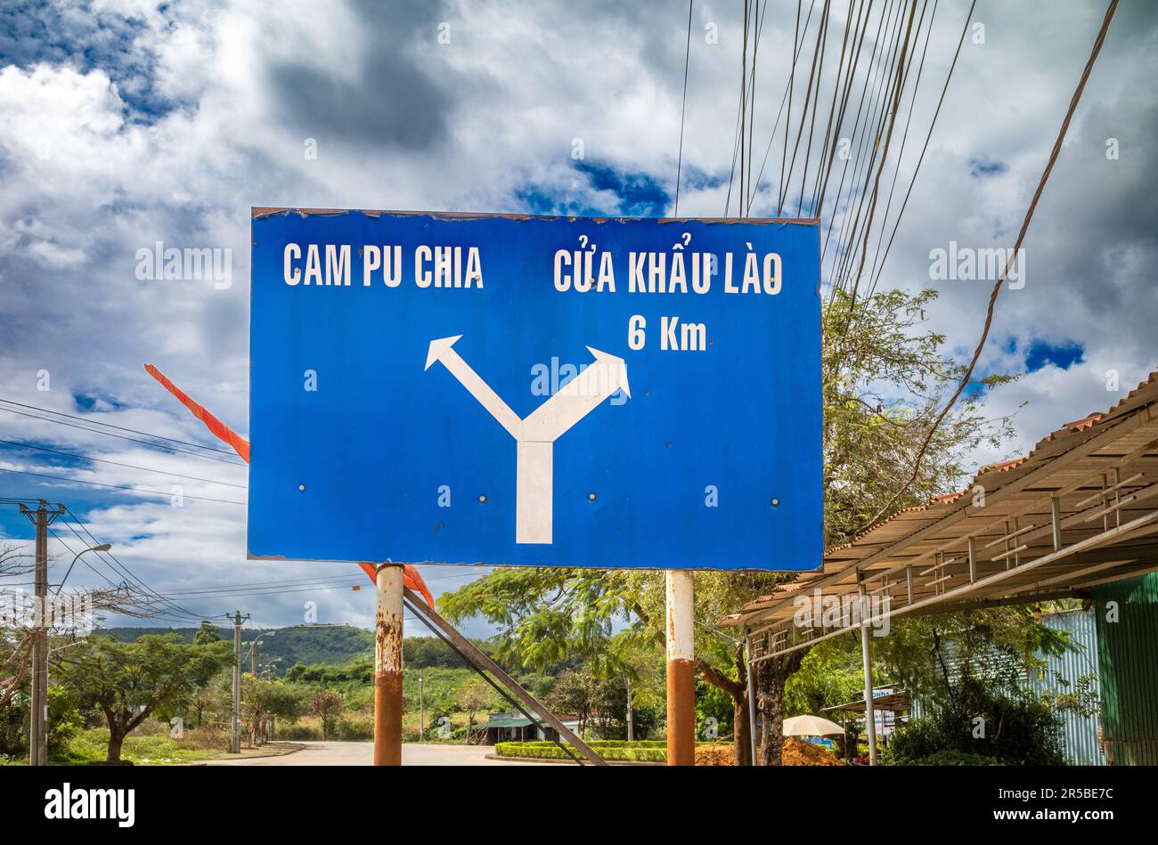 Un cartello stradale blu che indica i confini tra Cambogia e Laos nel comune di Bo Y, nel distretto di Ngoc Hoi, nelle Highlands centrali del Vietnam. Il segnale è Locate (individua) Foto Stock