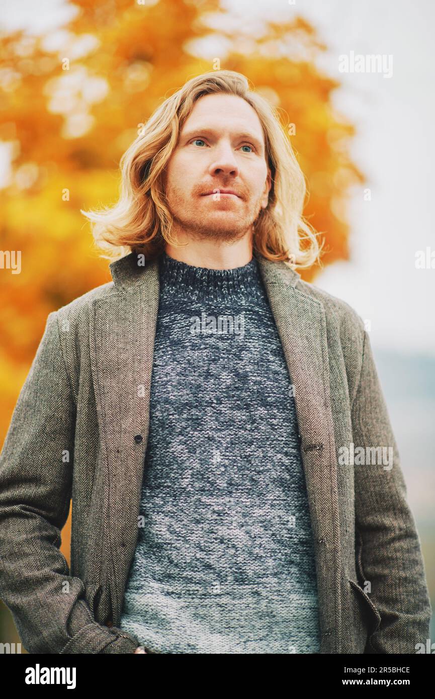 Ritratto all'aperto di un giovane uomo dai capelli rossi, con indosso un pullover e un cappotto, giorno di nebbia fredda Foto Stock