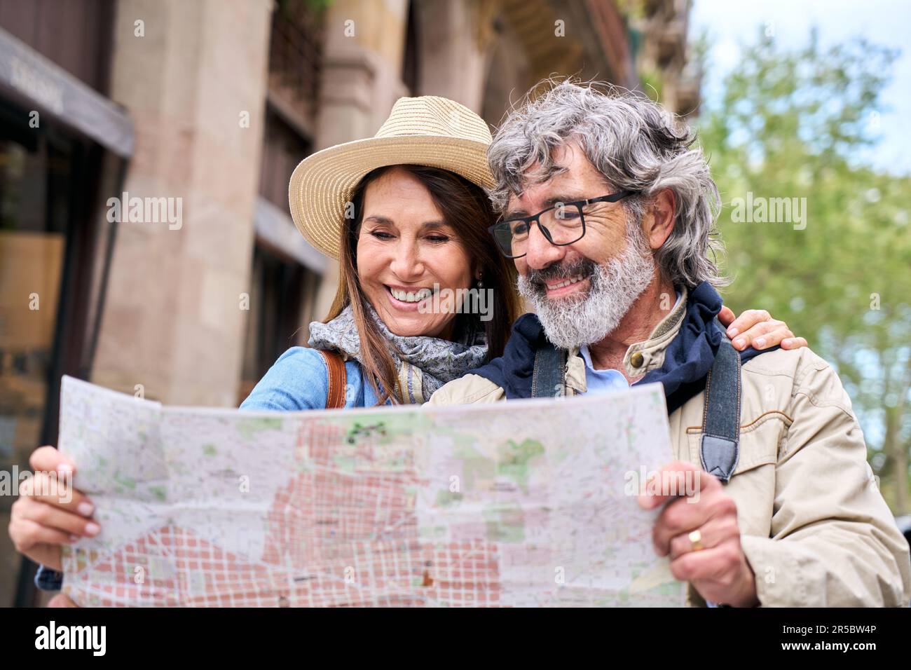 Coppia matura negli anni sessanta sorridente guardando la mappa in Europa città strada. Concetto di viaggio. Foto Stock