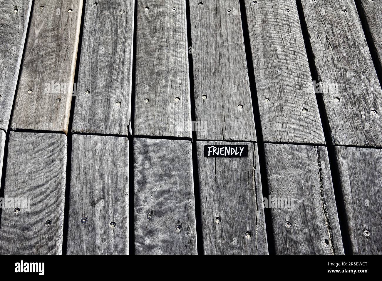 Un primo piano di una passerella di legno con un adesivo che dice amichevole a Melbourne, Australia Foto Stock