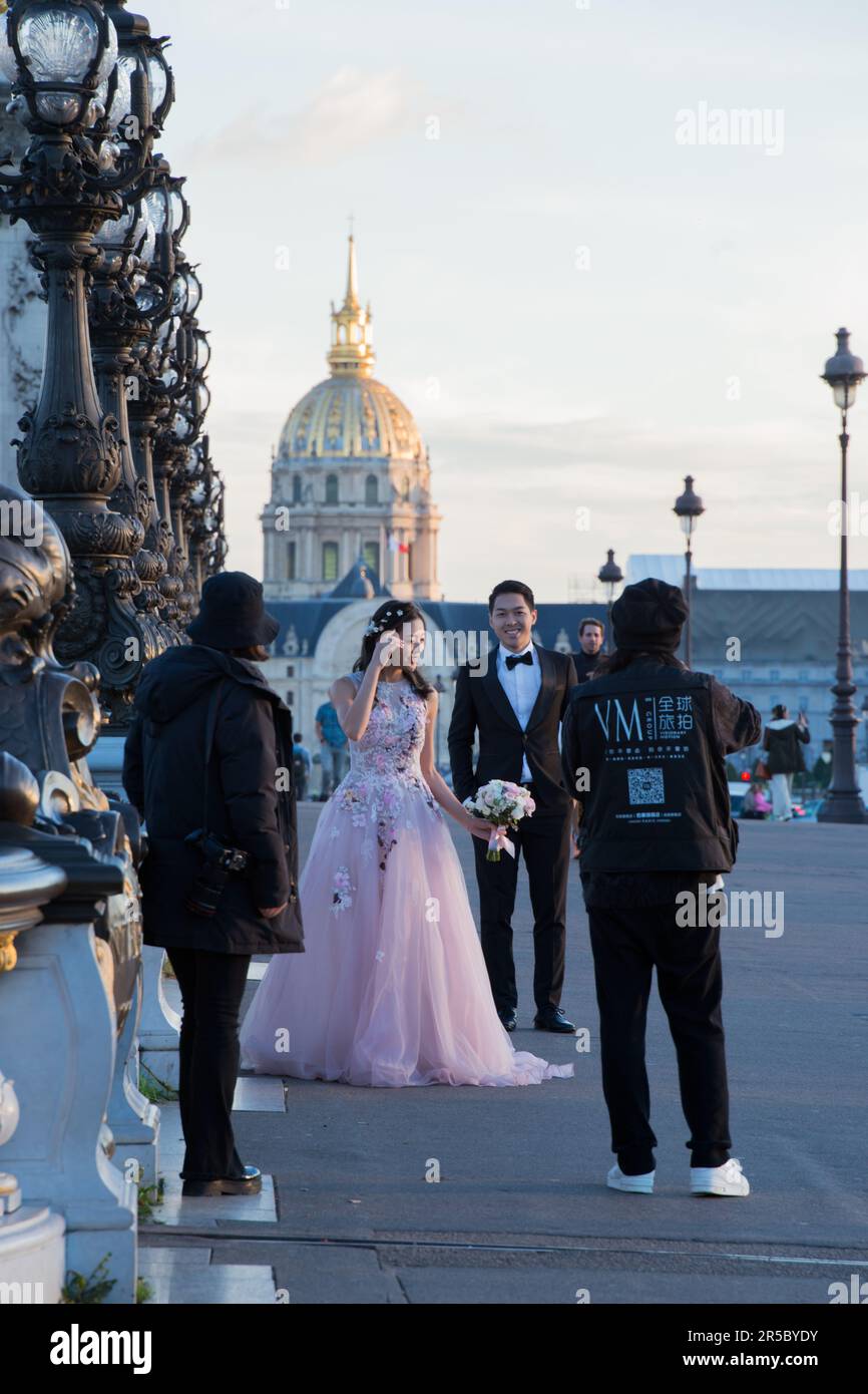 Un uomo che fotografa una giovane coppia felice durante il matrimonio a Parigi, in Francia Foto Stock