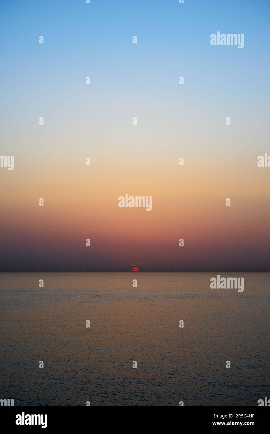 Una foto orientata verticalmente di un bel mare e cielo calmi all'alba Foto Stock