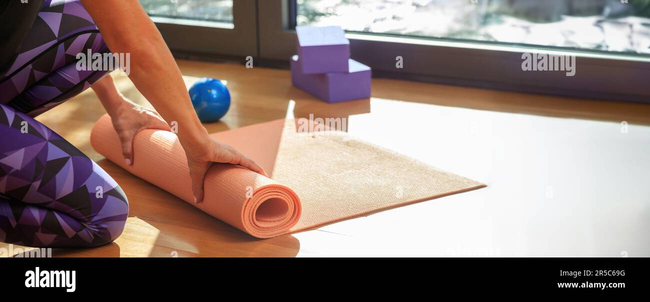 Interni in studio Pilates, concetto di allenamento e fitness. Istruttore che tiene un primo piano di materassino yoga Foto Stock