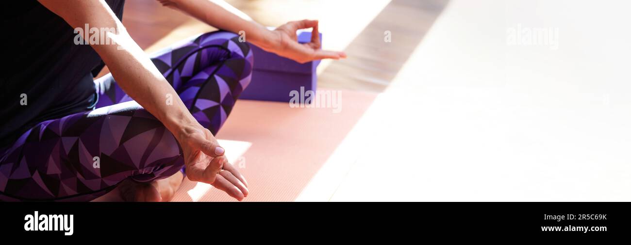 Interni studio di yoga. Istruttore di meditazione seduto in posa su un tappetino yoga, spazio copia Foto Stock