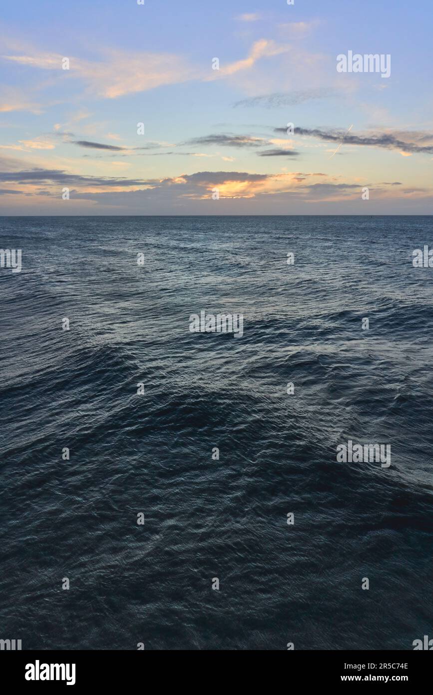 Una fotografia orientata verticalmente delle onde del mare sotto un cielo di alba di mattina presto Foto Stock