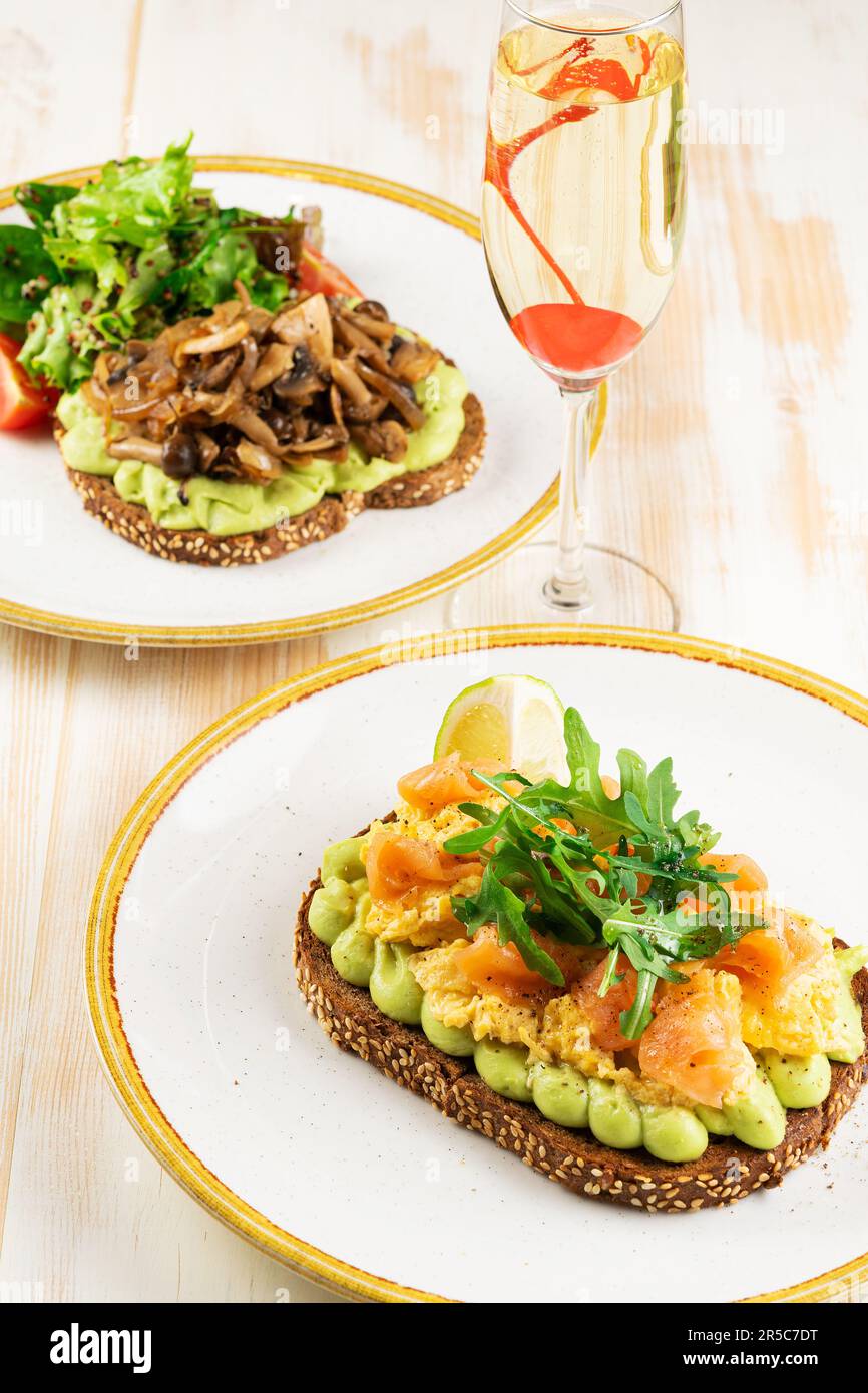 Due panini con salmone salato e funghi con un bicchiere di vino. Cibo sfondo. Foto Stock