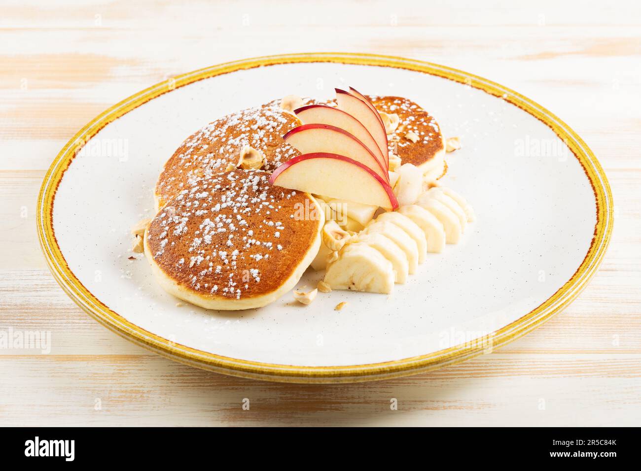 Frittelle con frutta su piatto bianco. Colazione gustosa. Foto Stock