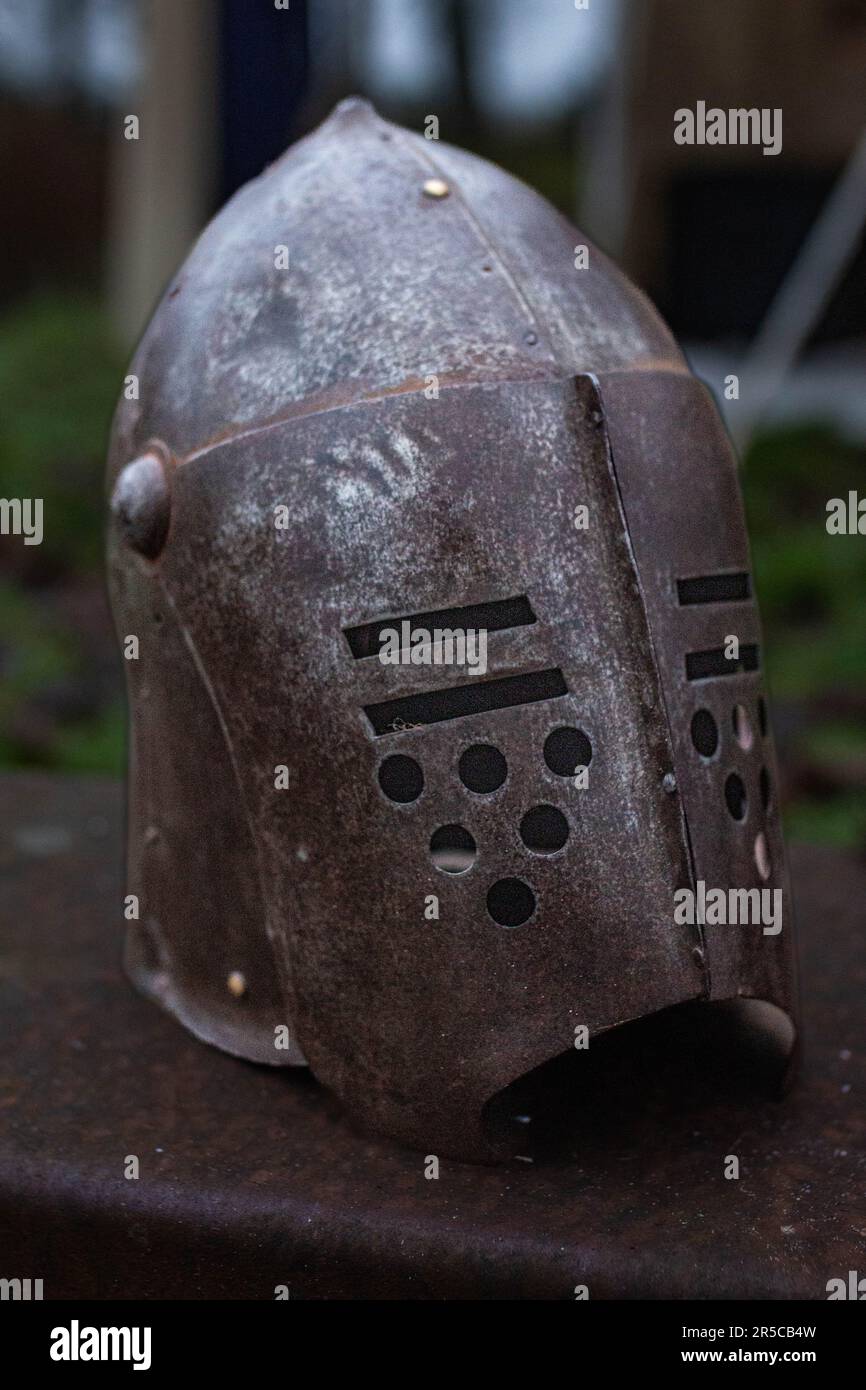 Un casco d'argento si trova in cima a un tavolo di legno, circondato da una lussureggiante erba verde in un ambiente naturale all'aperto Foto Stock