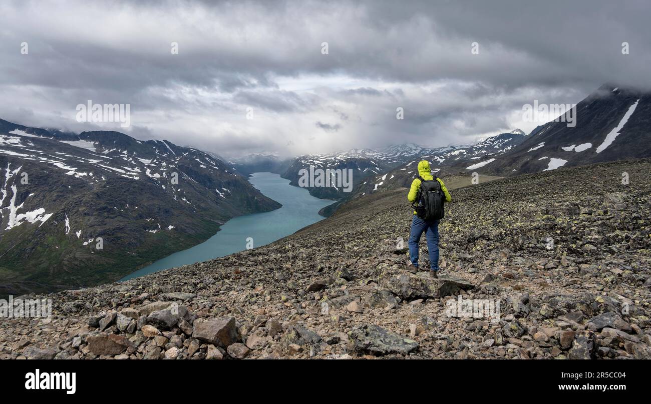 Arrampicatori su sentiero roccioso, escursione Besseggen, passeggiata sul crinale, vista sul lago Gjende e sulle montagne innevate, Parco Nazionale di Jotunheimen, Vågå, Innlandet, Norvegia, Euro Foto Stock