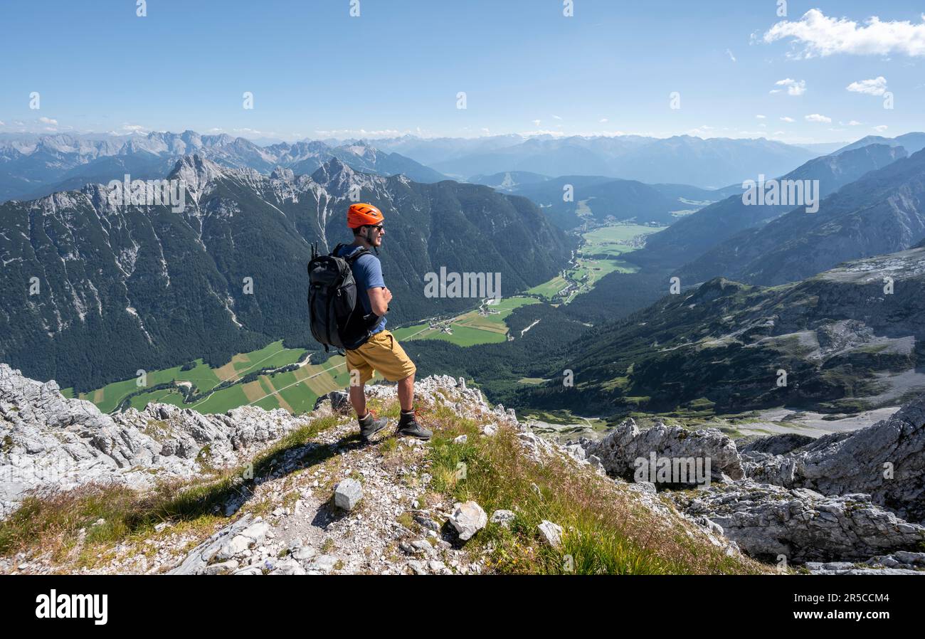 Alpinista alla cima dell'Obere Wettersteinspitze, vista sulla valle di Leutasch, sullo sfondo cima del Arnspitze, Wetterstein Foto Stock