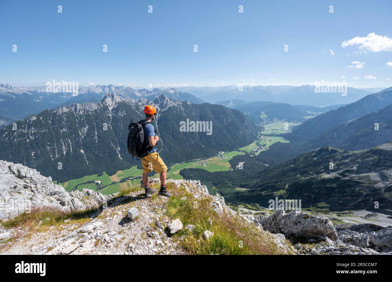 Alpinista alla cima dell'Obere Wettersteinspitze, vista sulla valle di Leutasch, sullo sfondo cima del Arnspitze, Wetterstein Foto Stock