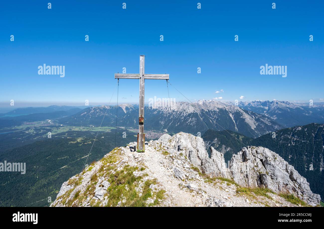 Croce sommitale sulla cima dell'Obere Wettersteinspitze, alle spalle dei Monti Karwendel, Monti Wetterstein, Alpi Bavaresi, Baviera, Germania Foto Stock