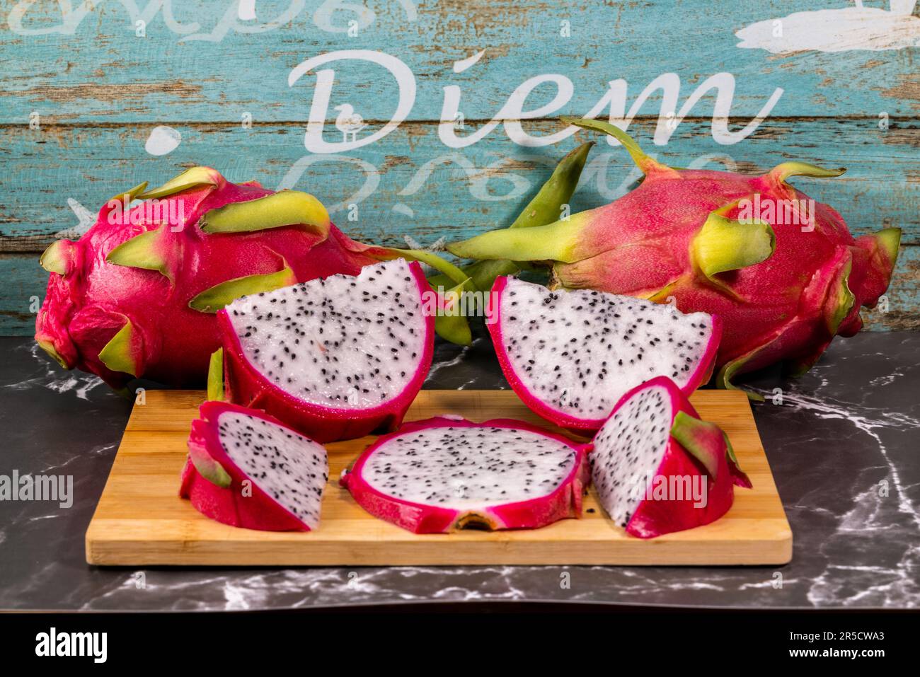 Una splendida composizione di frutti di drago su un tagliere di legno, che presenta un vibrante ed esotico mix di sapori Foto Stock
