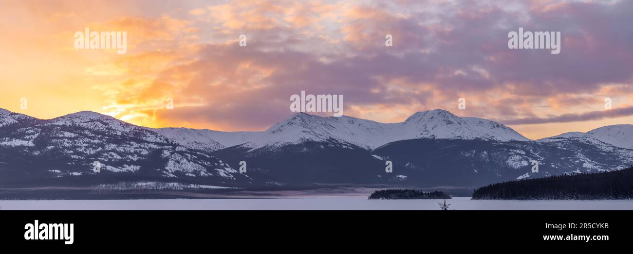 Viste panoramiche del tramonto nel nord del Canada all'inizio della primavera, nel tardo inverno con incredibili montagne innevate. Tagish, territorio dello Yukon. Foto Stock