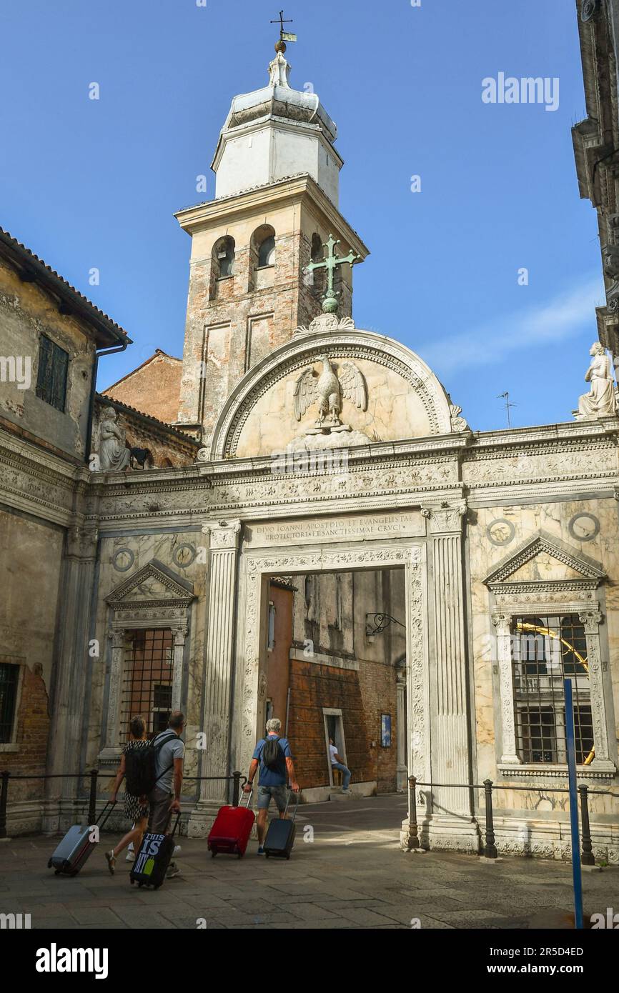 Un piccolo gruppo di turisti con trolley che arrivano nel cortile della chiesa della Scuola Grande di San Giovanni Evangelista in estate, Venezia, Veneto, Italia Foto Stock