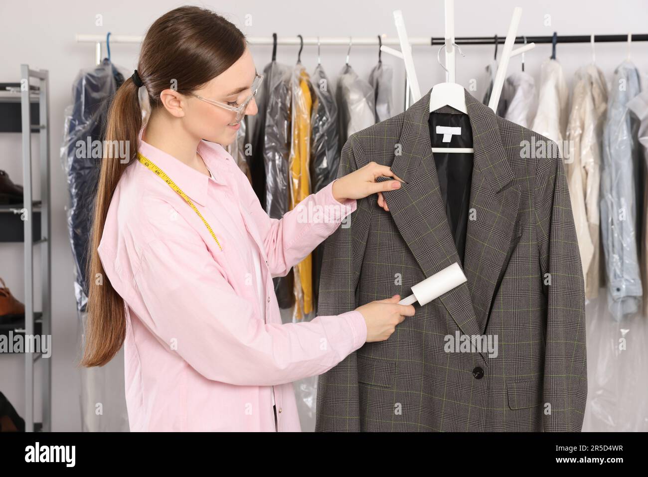 Giovane donna che usa un rullo per pelucchi adesivo a secco Foto Stock