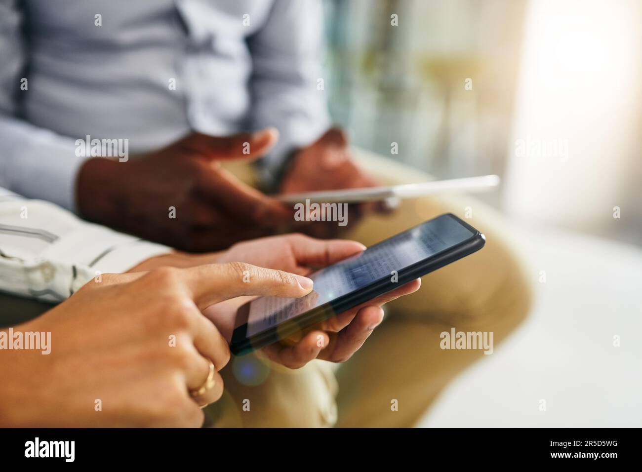 È l'era intelligente del business. Primo piano di due uomini d'affari che utilizzano dispositivi digitali in sincronia in un ufficio. Foto Stock