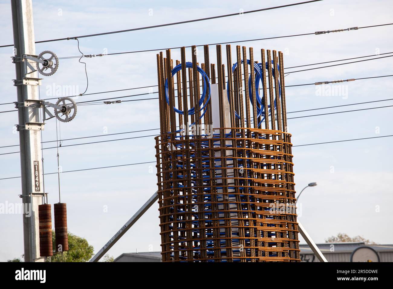 Ringhiera ponte di fondazione barre di armatura, una sovrastruttura in costruzione con condotto blu e linee elettriche. La grande costruzione di Victoria. Foto Stock