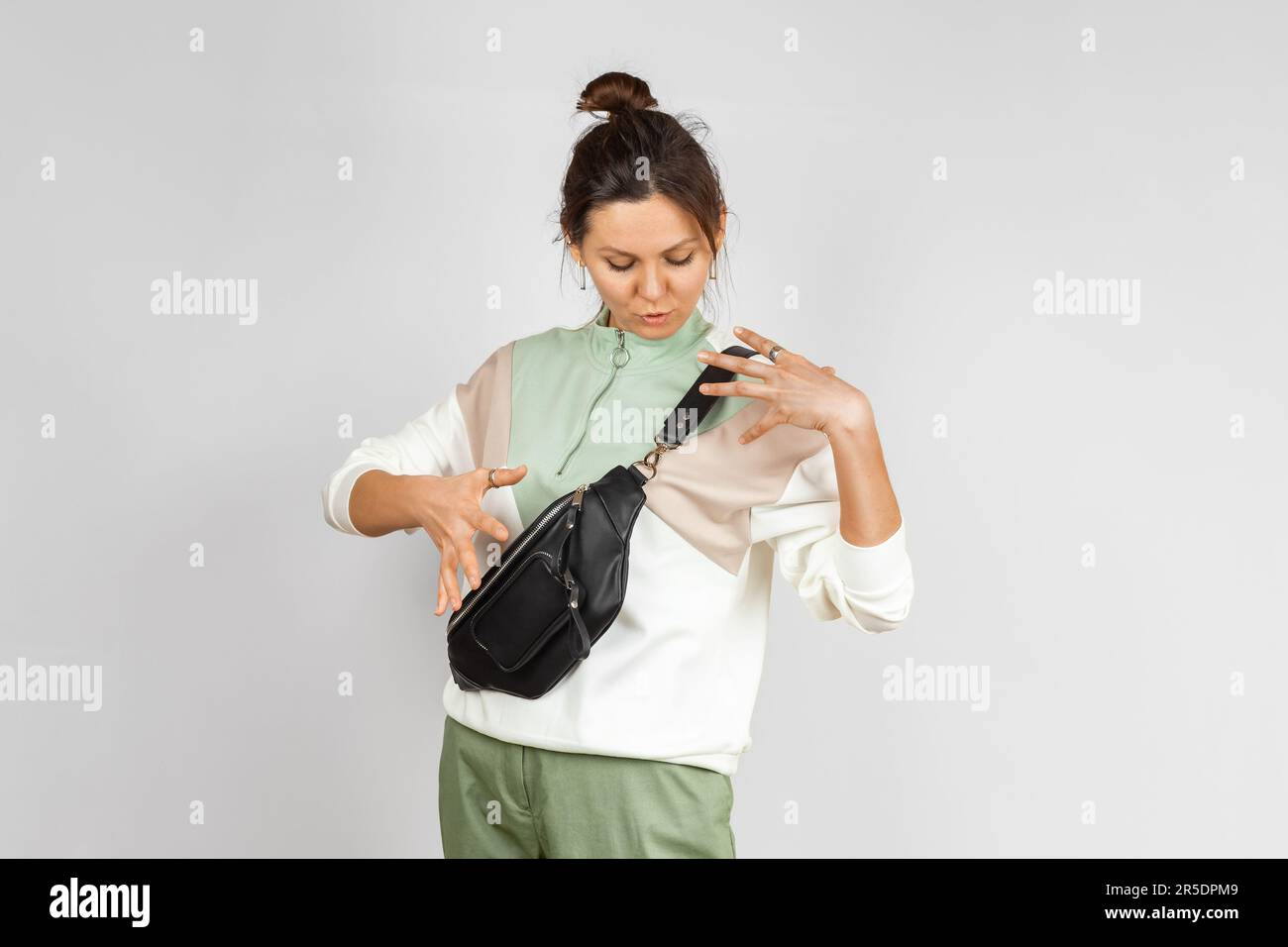 Donna che indossa una tracolla in una confezione in vita in vera pelle nera su sfondo grigio. Accessori in pelle fatti a mano Foto Stock