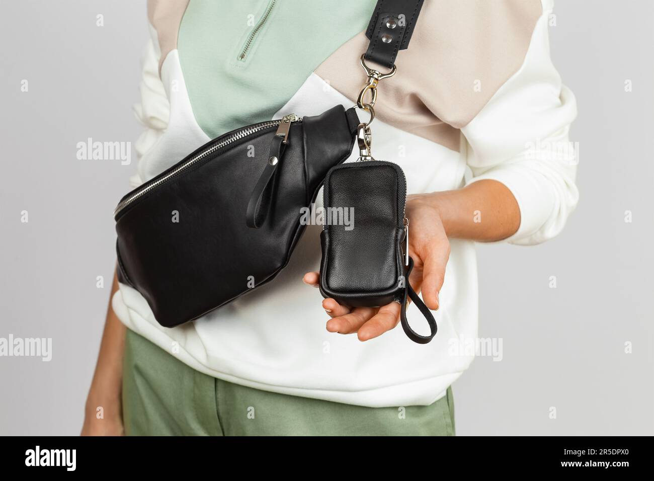 Piccola custodia in pelle per sigaretta elettronica fissata alla tracolla in Fanny Pack in vera pelle nera. Nessun modello Face Female su sfondo grigio, Stu Foto Stock