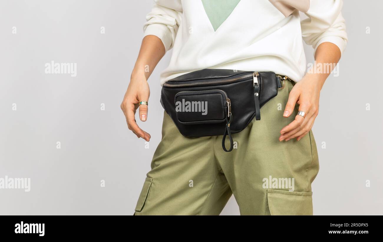 Borsa in vita in pelle nera per donna con pantaloni verdi e felpa. Accessori in pelle fatti a mano Foto Stock