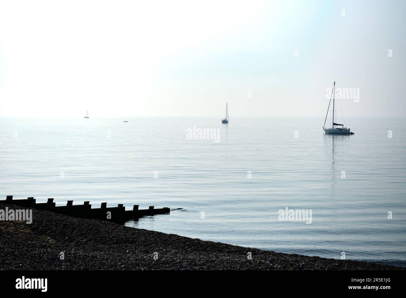 Immagine di alto-chiave degli yacht nel mare calmo al largo della spiaggia di Eastbourne nel Sussex orientale mentre la nebbia mattutina solleva. Foto Stock