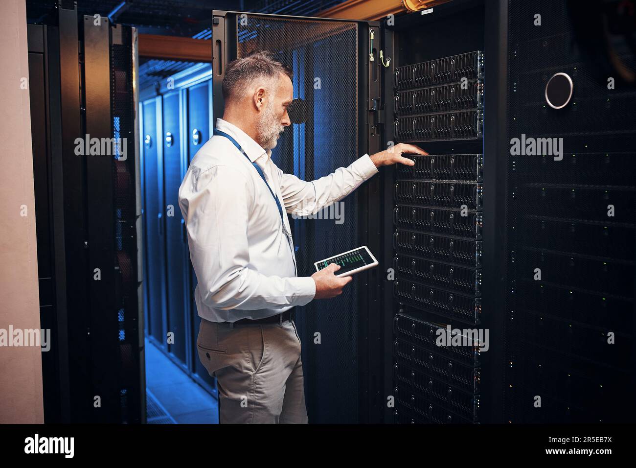 Proteggervi dalle minacce alla sicurezza informatica. un uomo maturo che utilizza un tablet digitale mentre lavora in una sala server. Foto Stock