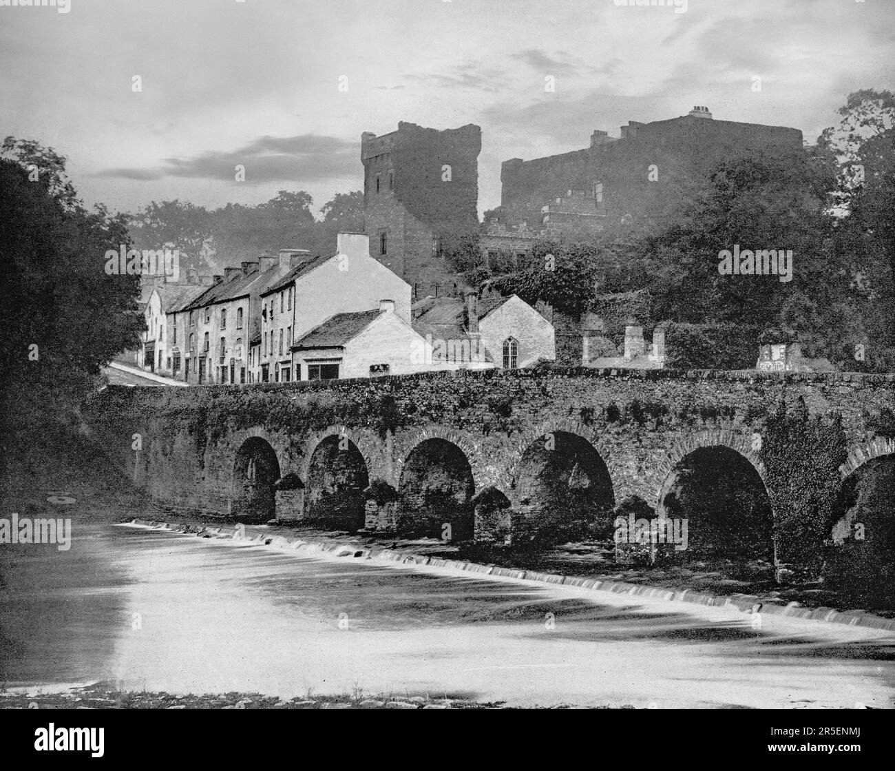 Una vista di fine '19th di Macroom, una città mercato nella contea di Cork, Irlanda. Macroom iniziò come luogo d'incontro per i druidi del 6th° secolo di Munster e in seguito ospitò una grande battaglia del 987 con la partecipazione del re irlandese Brian Boru. Oltre il ponte sul fiume Sullane si trova il Macroom Castle, che è stato assediato, bruciato e ricostruito. Foto Stock
