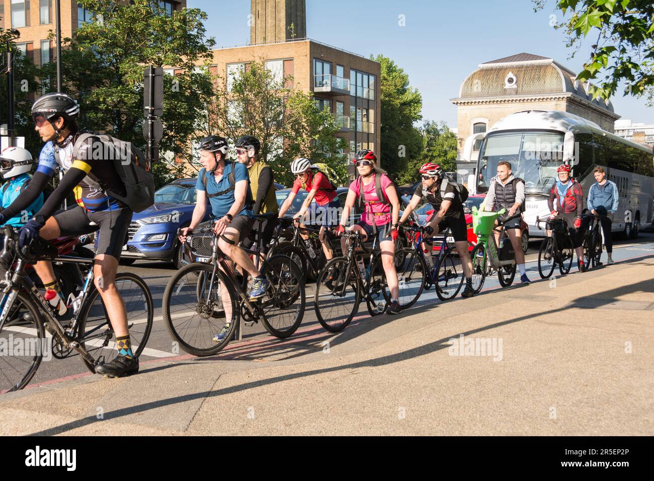 Un gruppo di colorati ciclisti londinesi sulla Cycle SuperhHighway 8 in attesa che il semaforo cambi su Grosvenor Road, Londra, SW1, Inghilterra, Regno Unito Foto Stock