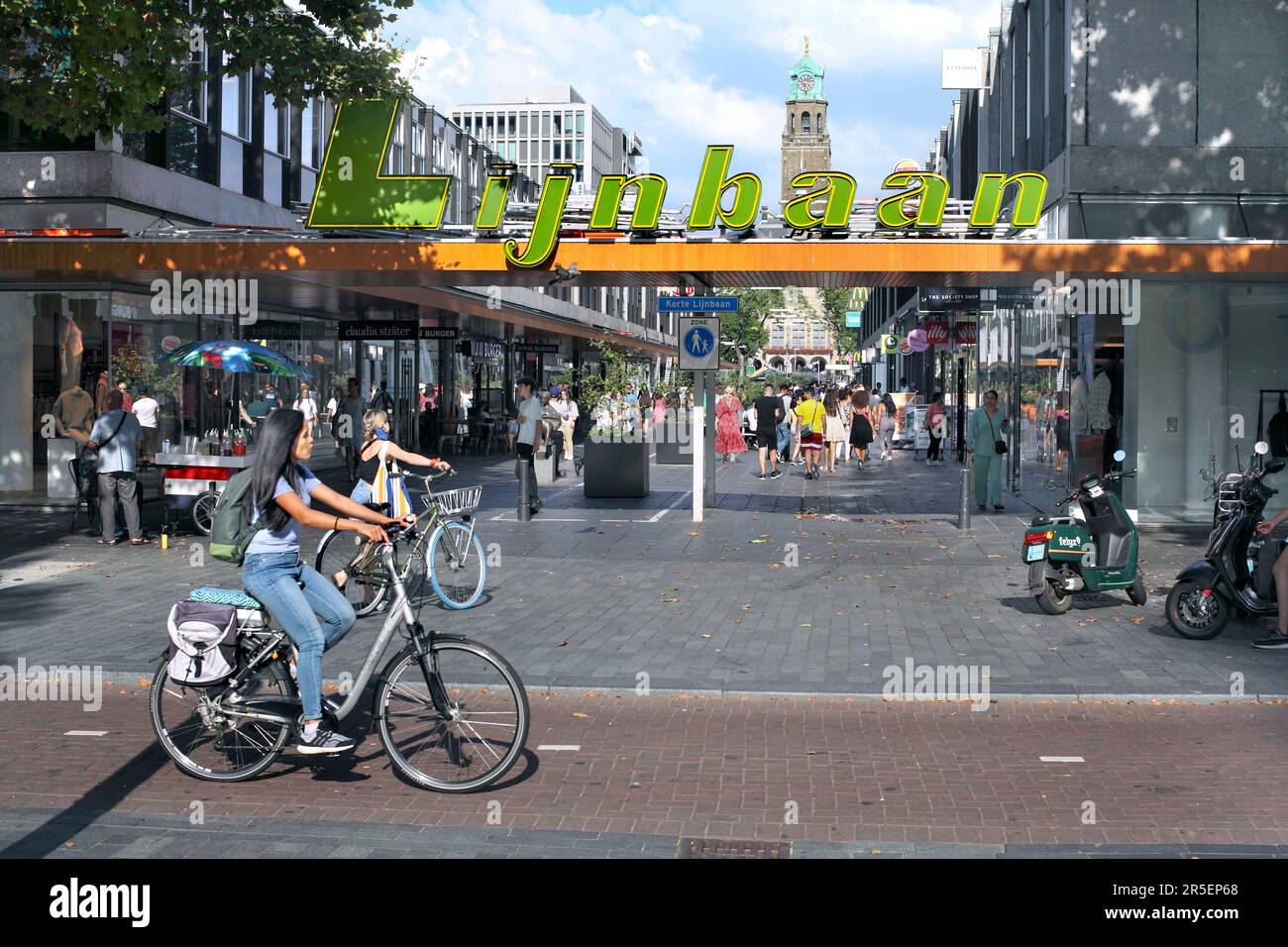 Un ciclista su una pista ciclabile che attraversa il quartiere commerciale Lijnbaan a Rotterdam, la pista per il giardinaggio olandese Foto Stock