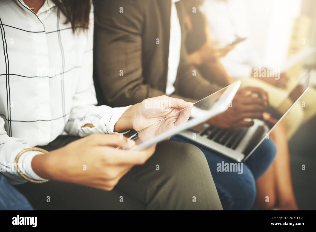 Connettiti a un mondo di informazioni aziendali. gruppo di imprenditori che utilizzano i dispositivi wireless mentre sono in attesa in linea. Foto Stock