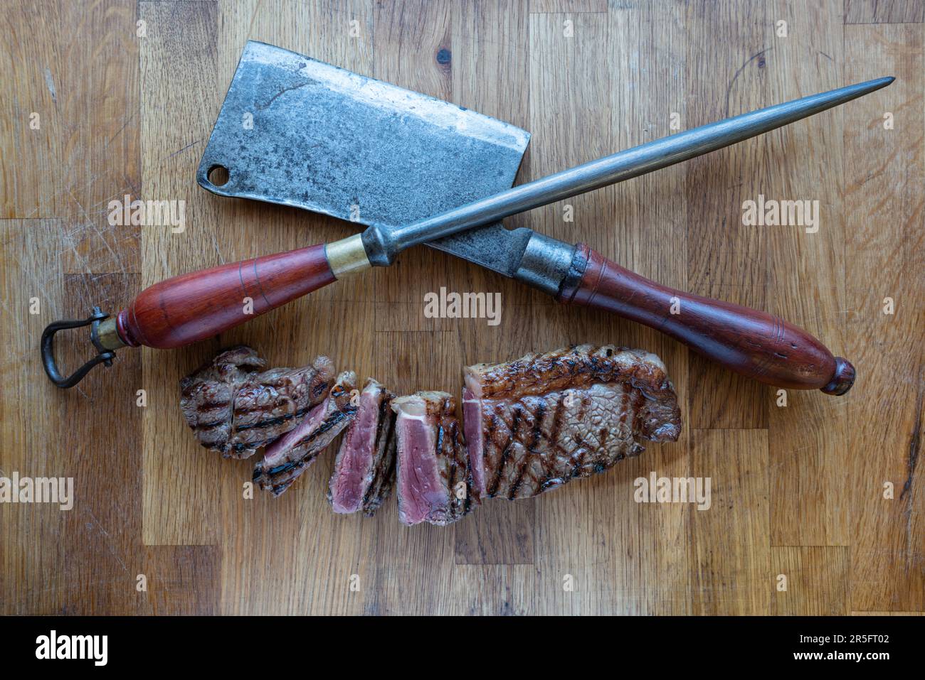 Bistecca di controfiletto affettato su un tagliere di legno, completata da un tritatutto di carne rustico, una miscela di tradizione e sapore. Foto Stock
