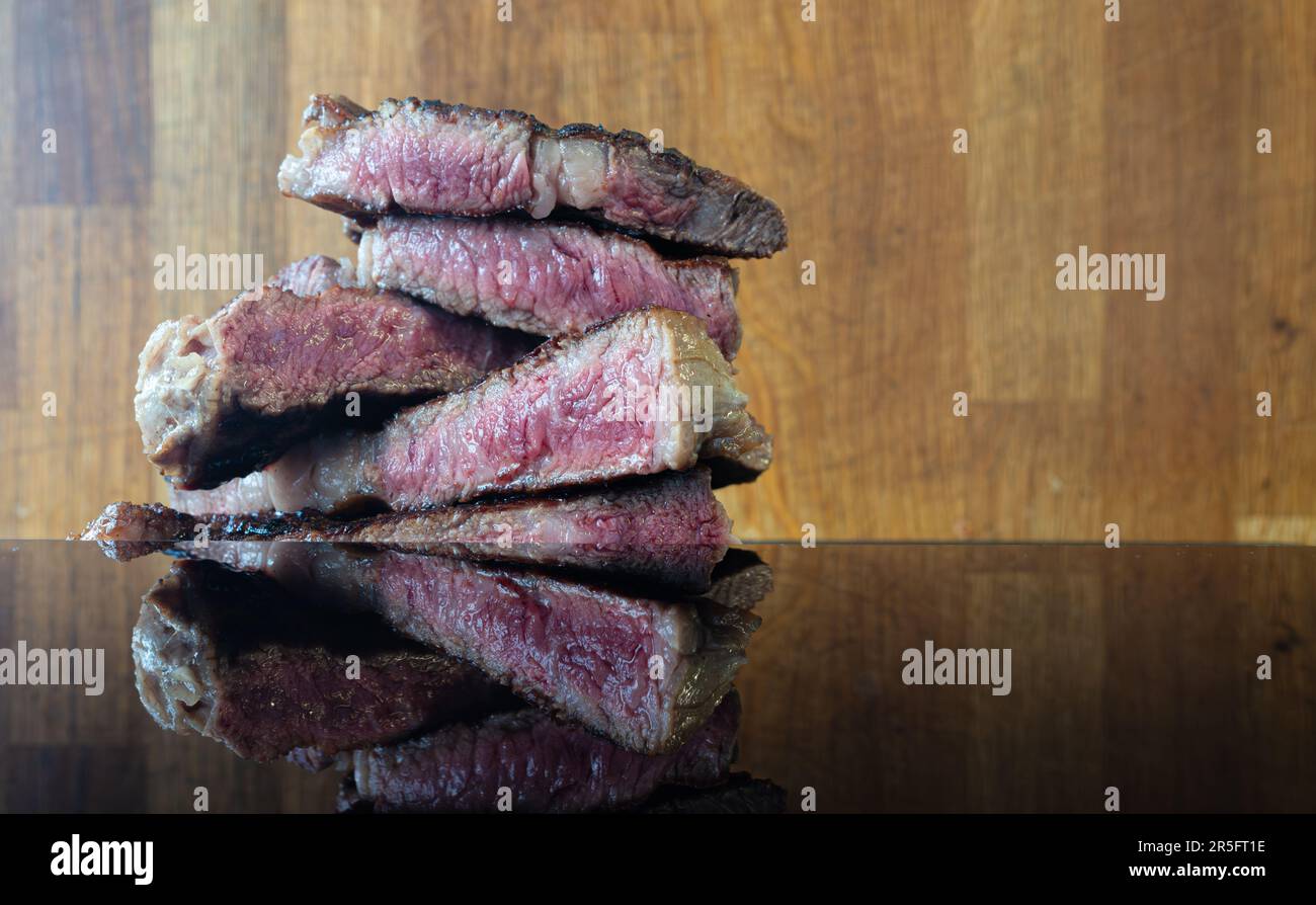 'Assaporate l'essenza di una bistecca di manzo alla griglia, perfettamente affettata, splendidamente catturata su uno sfondo rustico in legno, una festa per i sensi. Foto Stock