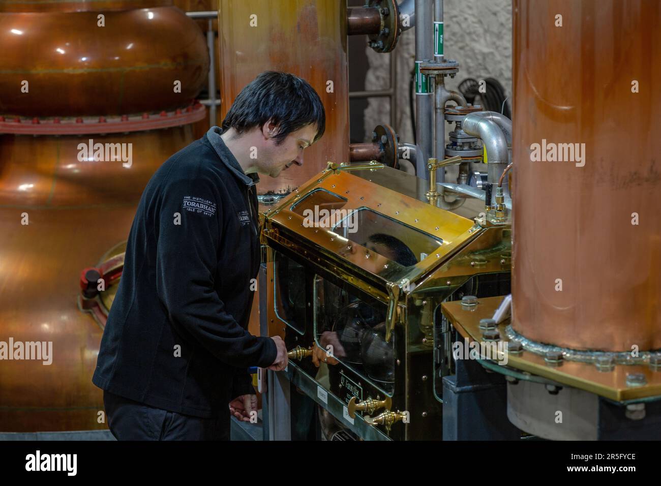 Ancora l'uomo controlla i livelli di alcool nella cassaforte di spirito alla distilleria di Torabhaig sull'isola di Skye, Scozia Foto Stock