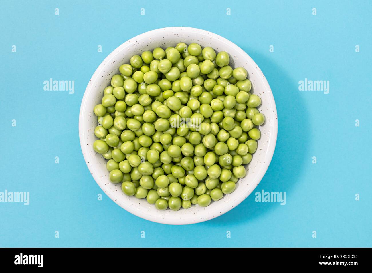 Piselli freschi verdi in ciotola isolato su fondo blu. Vista dall'alto Foto Stock