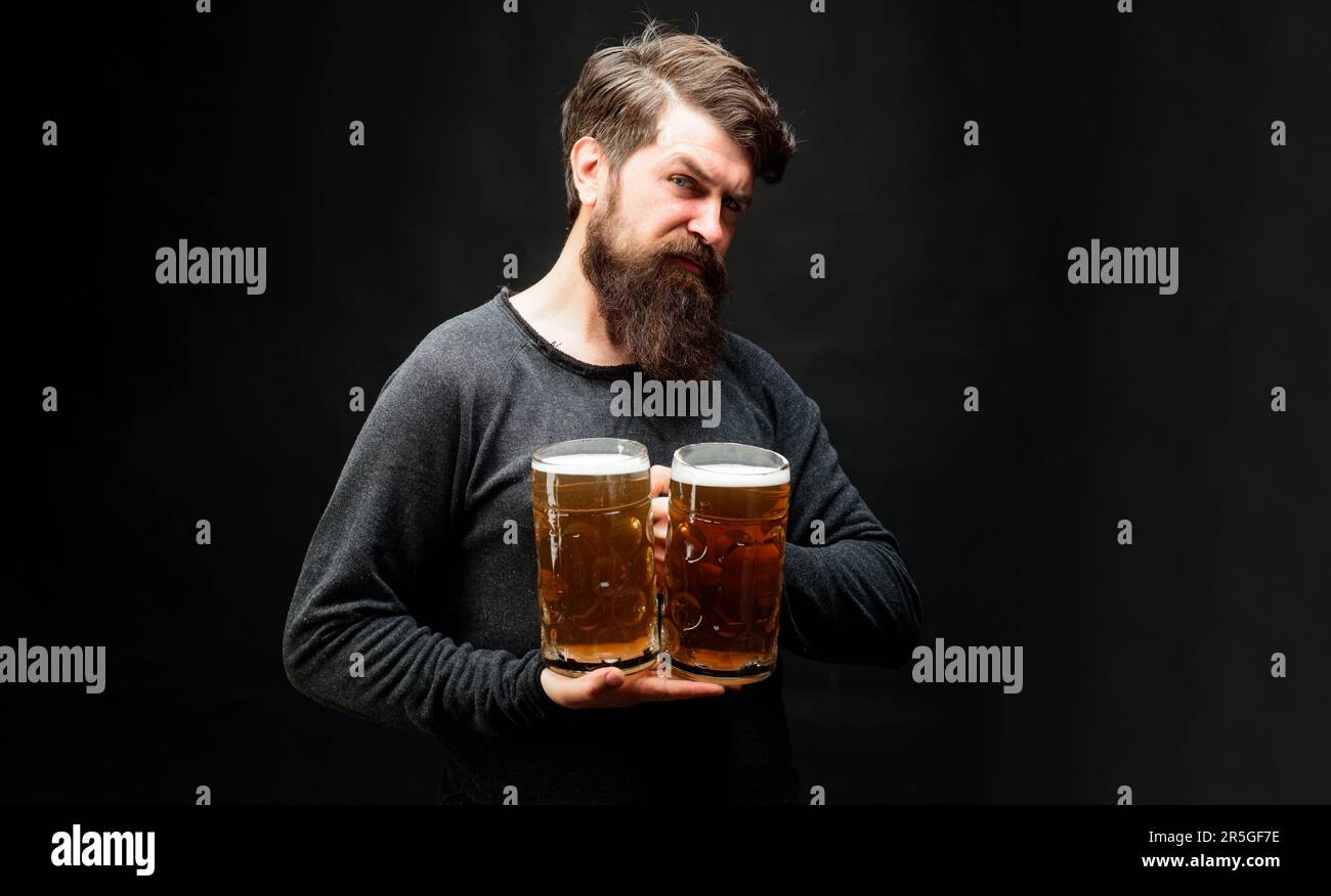 Barbuto con brocche di birra lager al bar o pub. Ragazzo alla moda con birra artigianale. Barbuto maschio degustazione birra fresca di birra. Oktoberfest festival. Birra Foto Stock