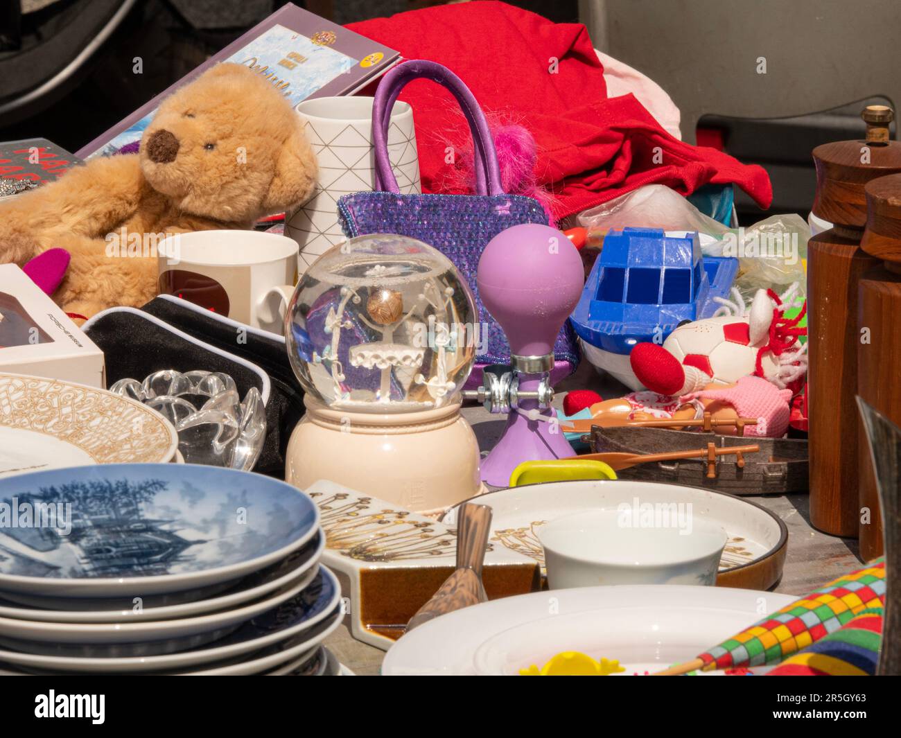 Giocattoli per bambini e piatti esposti su un tavolo al mercato delle pulci. Foto Stock