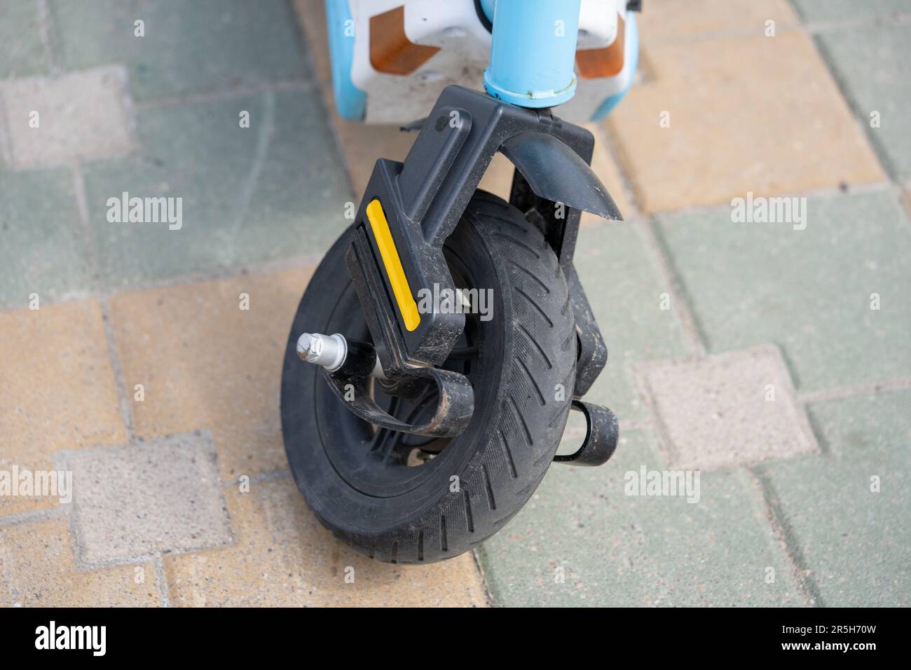 Primo piano della ruota anteriore dello scooter elettrico rotta su sfondo asfalto grigio Foto Stock