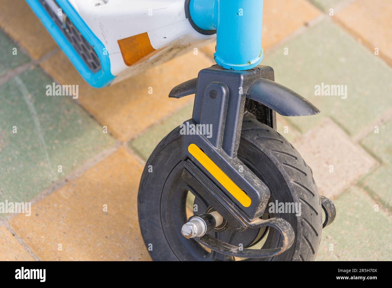 Primo piano della ruota anteriore dello scooter elettrico rotta su sfondo asfalto grigio Foto Stock