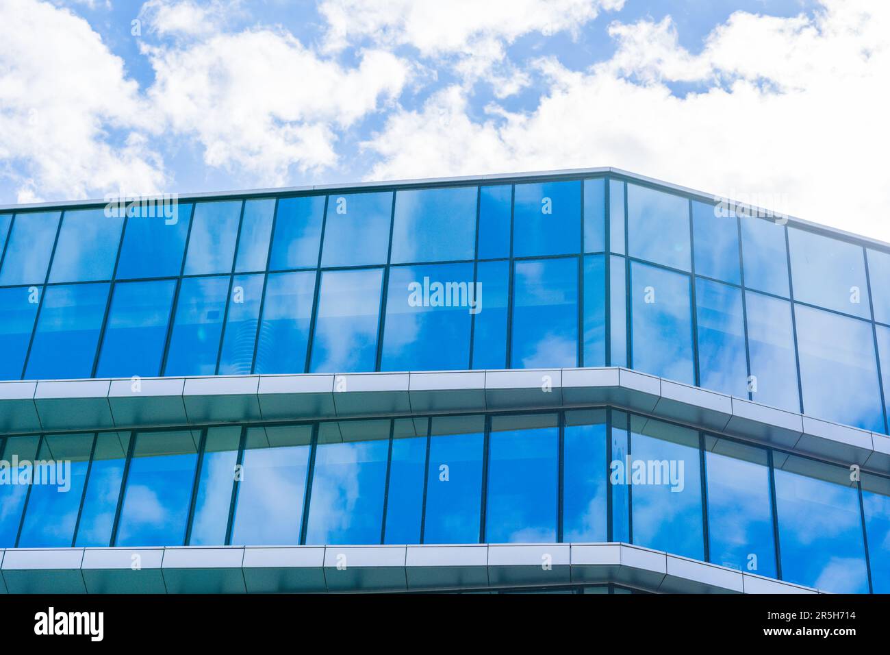 Futuristica Torre di vetro con una splendida facciata blu e nuvole bianche nel cielo Foto Stock