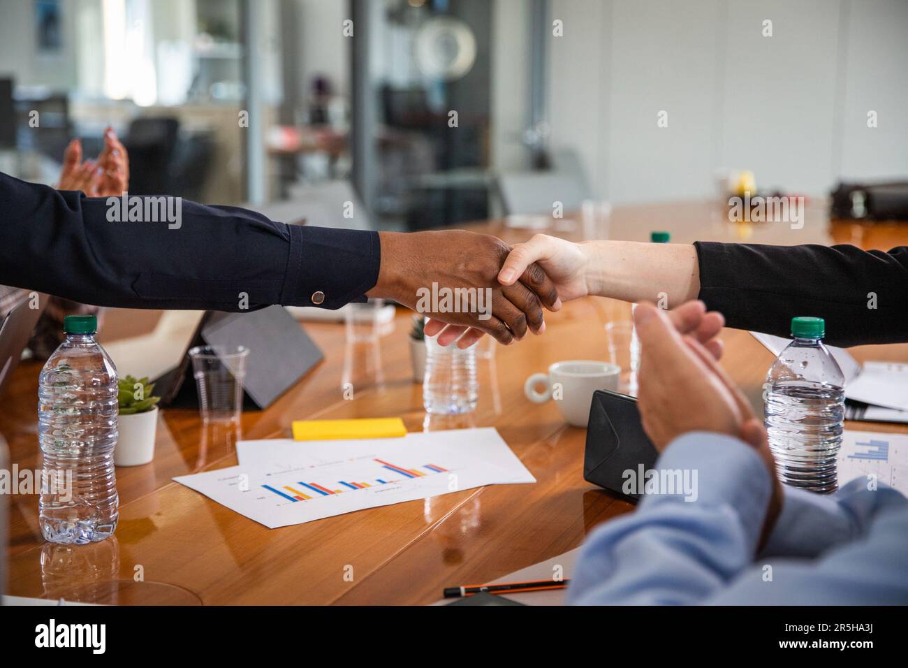 Durante una riunione in una sala conferenze, è possibile fare una stretta di mano tra due persone di diverse etnie. Foto Stock