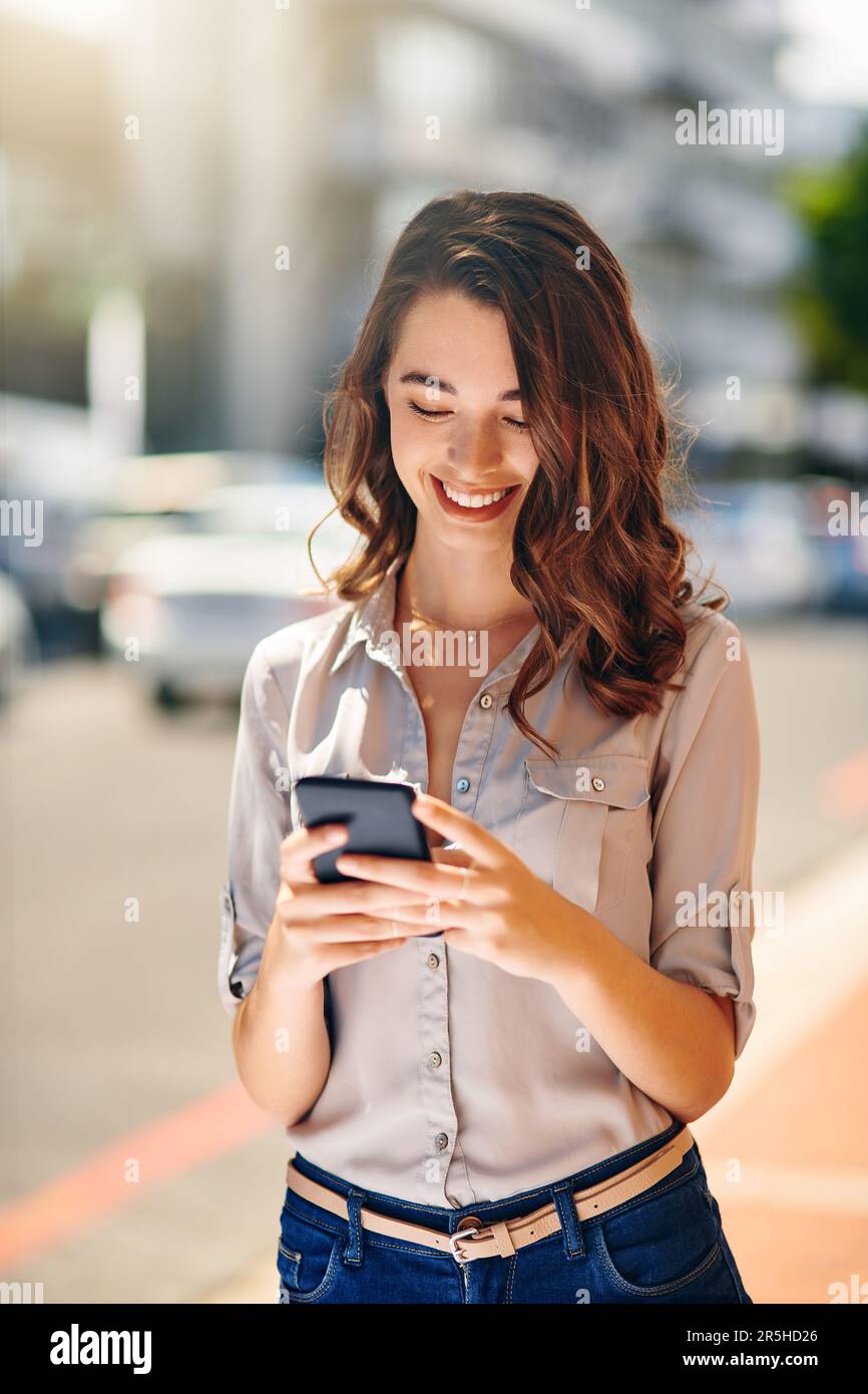 Alcuni messaggi ti fanno sorridere. una giovane e attraente donna d'affari che invia messaggi di testo durante il suo viaggio mattutino al lavoro. Foto Stock
