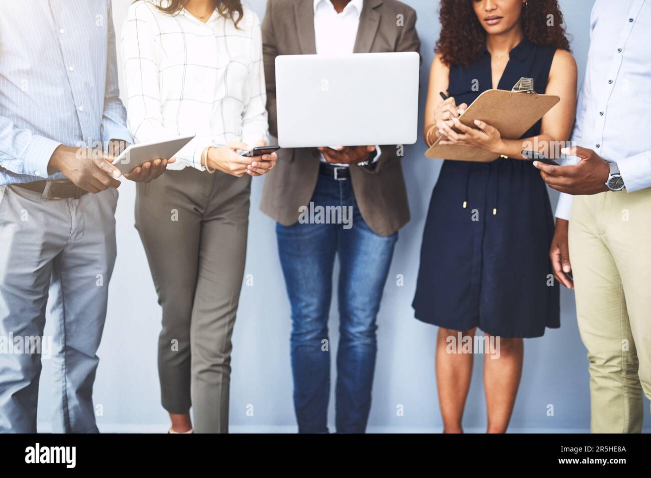 Riunirsi e diventare produttivi. Studio di un gruppo di uomini d'affari che utilizzano i loro dispositivi wireless mentre sono in attesa in linea. Foto Stock